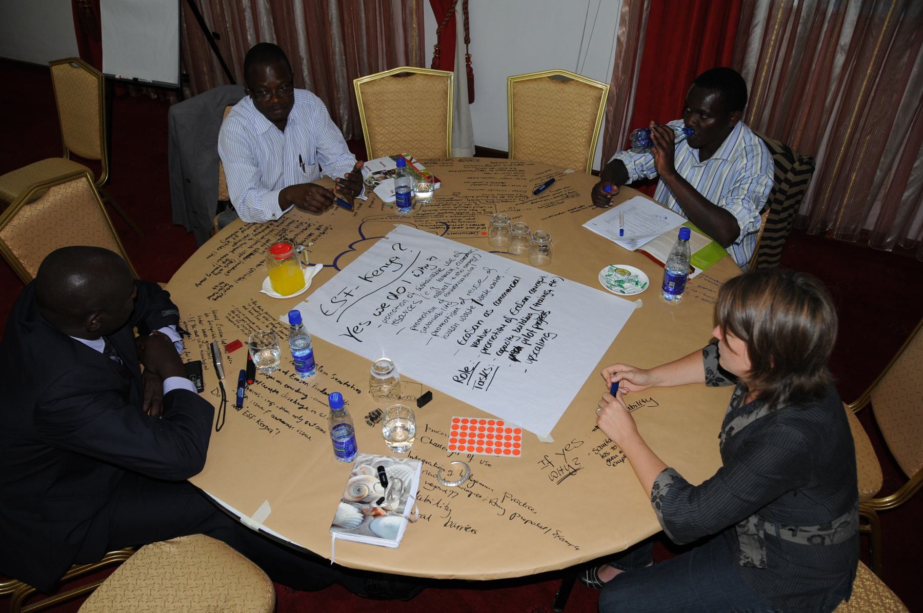 Programme partners working through plans on a flipchart at a round-table workshop in Kenya