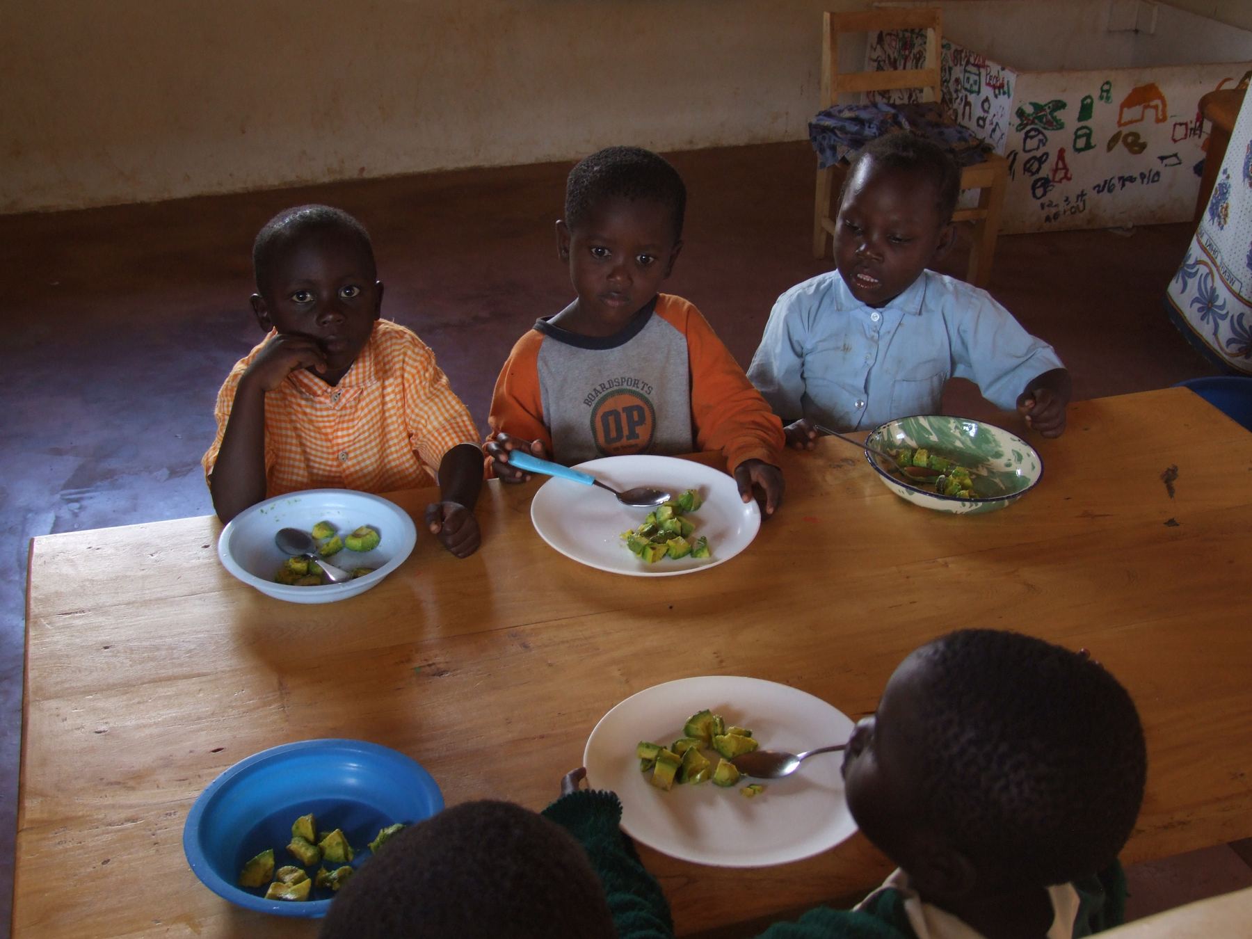 Young pupils eating a school meal together at a table in Kenya